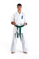 Young karate man in fudo dachi position on white background. With the word kyokushinkai on the background. Which means: the last truth associated.