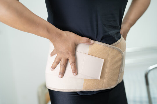 Asian lady patient wearing back pain support belt for orthopedic lumbar.