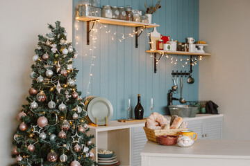 Kitchen in a modern style, decorated for the new year: Christmas tree, plates, a bottle of champagne, glasses and shelves with jars for storing cereals