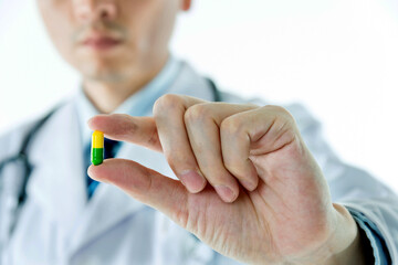 Male doctor holding a pill between his fingers