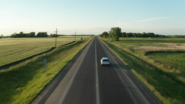 Aerial, white SUV family car driving on farmland countryside paved asphalt road 