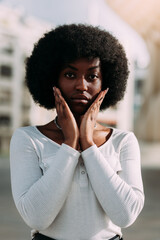 Fototapeta na wymiar Portrait of a young black woman with afro hair gesturing with her hands in a v shape. Vertical
