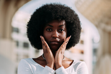 Portrait of a young black woman activist with afro hair gesturing with her hands in a v shape. Horizontal