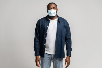 African-American man in protective medical mask standing and looking at the camera, guy keeps himself in safety during pandemic, isolated