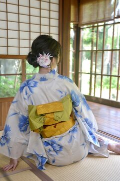 古民家の和室でくつろぐ浴衣を着た若い女性の後ろ姿	