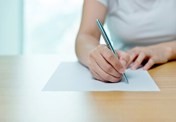 Hand of woman writing on paper in office