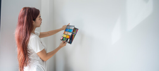 Asian woman choosing house paint color from catalog, Asian woman using colored charging pads to choose the color of the walls of the house.