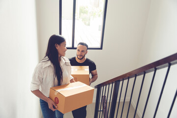 Thai and Caucasian couple holding boxes of things walk up stairs to move into a new home with fun