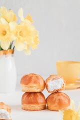 Round mini eclairs or profiteroles with whipped cream on a blurred background. French breakfast concept.