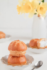 Traditional french breakfast with mini eclairs with white cream. Round eclairs or profiteroles on a white plate.