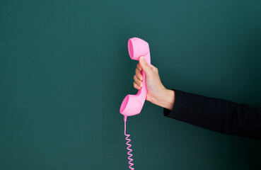 Woman hand holding vintage telephone receiver isolated on green background - Powered by Adobe