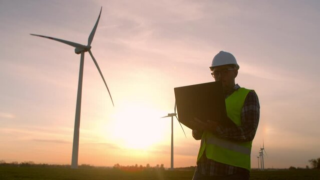 Windmill engineer. engineer at a wind farm with a tablet in his hand at sunset.
