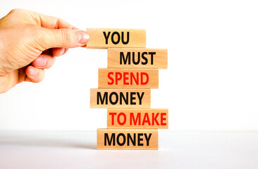 Spend and make money symbol. Wood blocks with words You must spend money to make money. Beautiful white table white background Businessman hand. Business spend and make money concept. Copy space.