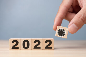 Hand putting wooden cubes 2022 with goal icon on table and grey background, copy space. Start new year 2022 with goal plan, goal concept, action plan, strategy, new year business vision.