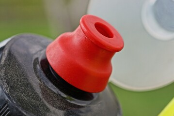 part of a black plastic water bottle closed by a red cap on a bicycle on a white background