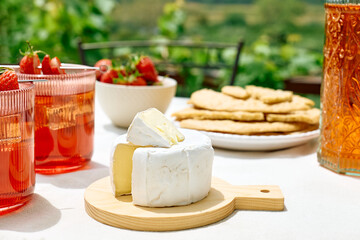 Cozy spring or summer breakfast or brunch outside on the table. Strawberry mocktail, camembert cheese, flat crispbread on linen tablecloth. Healthy snack. Picnic.