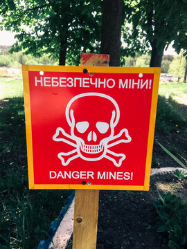 Sign with the inscription in English and Ukrainian "Danger Mines". Minefield warning