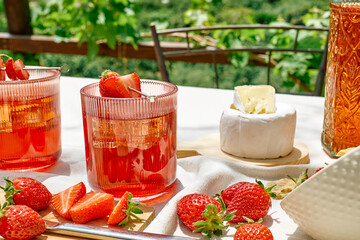 Cozy spring or summer breakfast or brunch outside on the table. Strawberry mocktail, camembert cheese, flat crispbread on linen tablecloth. Healthy snack. Picnic.