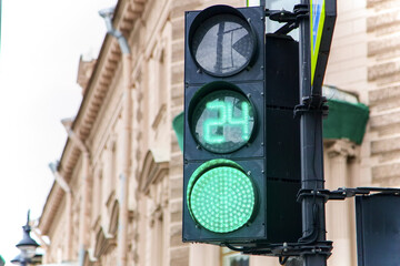Traffic light glows green close-up on a blurred background of the streets. Means of traffic regulation on the roads of the city. Rules of conduct on the roadway.