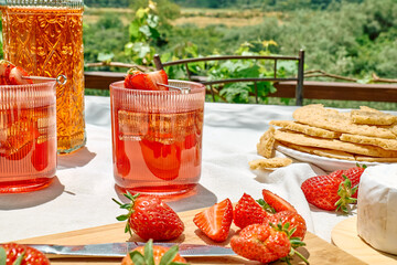 Cozy spring or summer breakfast or brunch outside on the table. Strawberry mocktail, camembert cheese, flat crispbread on linen tablecloth. Healthy snack. Picnic.
