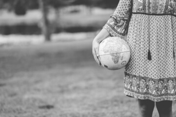 Grayscale shot of a Caucasian female holding a globe in the park