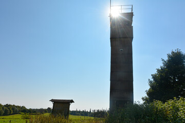 Fototapeta na wymiar An old watchtower of a former GDR border fortification in the back light with the sun
