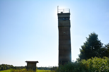 An old watchtower of a former GDR border fortification in the back light with the sun