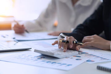 Business people pointing graph and using calculator during a business meeting.