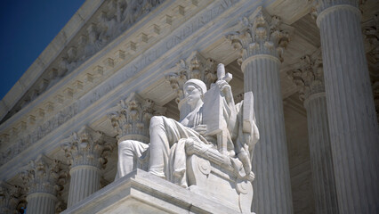 Closeup of sculpture on the Supreme Court building of Justice with Equal Justice slightly out of focus in the distance.