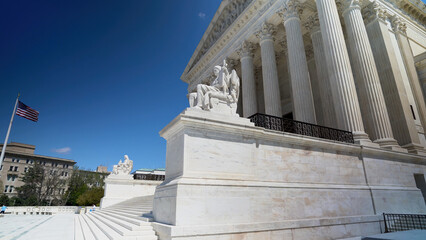 Side of the Supreme Court building in Washington, DC with a clear blue sky in the spring.