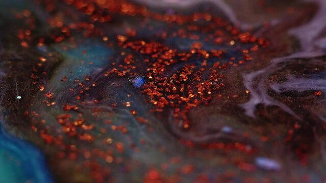 Glitter fluid mix. Ink water background. Sparkling liquid flow. Blur red color shiny sequins floating on blue purple paint abstract marble texture.
