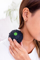 Vertical shot of a woman massaging her neck by the mini vibrating hand massage ball © Orlando Rafael Nieto Chumbipuma/Wirestock Creators