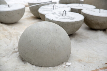 City car parking limiter in the form of a gray concrete hemisphere, a warehouse of a reinforced concrete plant.