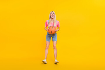 Full length body size view of attractive cheerful girl holding throwing ball playing isolated over bright yellow color background