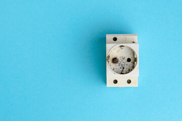 Burnt din socket after a short circuit in the electrical network. The concept of electrical safety. Blue background, flat lay, space for text.