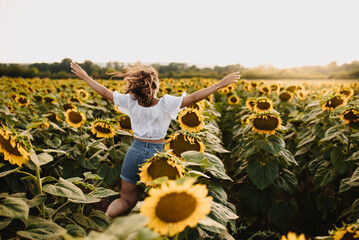 Unrecognizable girl admiring the scenic view of the sunflower field in summer