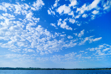 White clouds in the blue sky. Summer sky. Curly clouds on a sunny day. Heaven and infinity. Beautiful bright blue background. Light cloudy, good weather