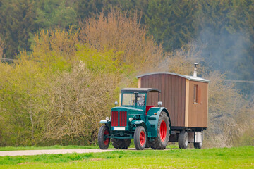Oldtimer vintage agricultural tractor towing a wooden cabin trailer