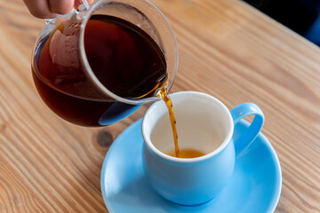 コーヒーポットでカップにコーヒーを注ぐ
