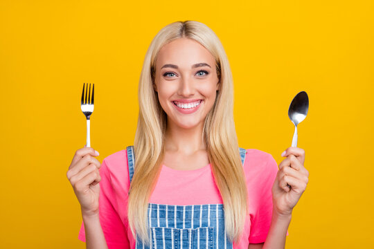 Portrait of attractive cheerful girl holding cutlery ready to have tasty meal isolated over bright yellow color background