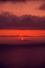 Fototapeta premium Meditative calmness and greatness. Red sun in the clouds. Colorful sunset in the evening sky. Amazing sky panorama. Clouds illuminated by the setting sun. Great dramatic view
