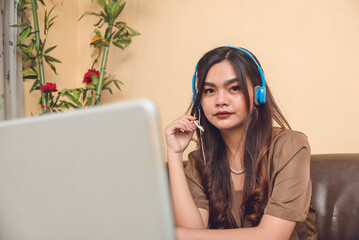 A beautiful customer service representative working remotely at her living room. A call center...