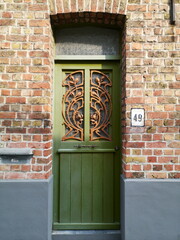 Alte grüne Holztür mit Fenster und Schmiedeeisen in einer alten rotbraunen Backsteinfassade in...