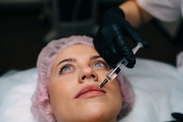 Beautician do botox injection with syringe to girl