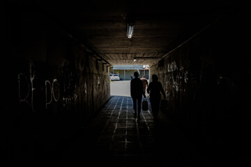 people walking in dark tunnel returning from shopping.