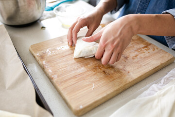 woman preparing spanikopita with phyllo dough on wooden cutting board