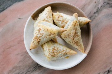 Homemade spanikopita triangles on ceramic plate sitting on coffee table