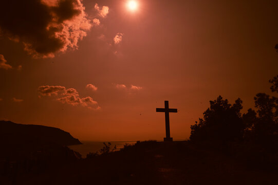 Evening landscape. The Cross of God on the hill in cloudy weather. A picture on a warm orange sunset day.