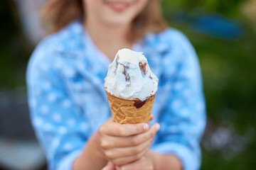 Unrecognizable girl with italian ice cream cone in hand, resting in park on summer day