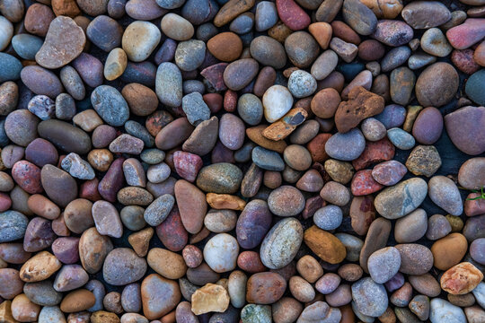 Mineral background featuring river stones in muted colors scattered evenly on the ground, high angle close-up view of small pebbles laid flat, aesthetic mood board backdrop inspiration with copy space